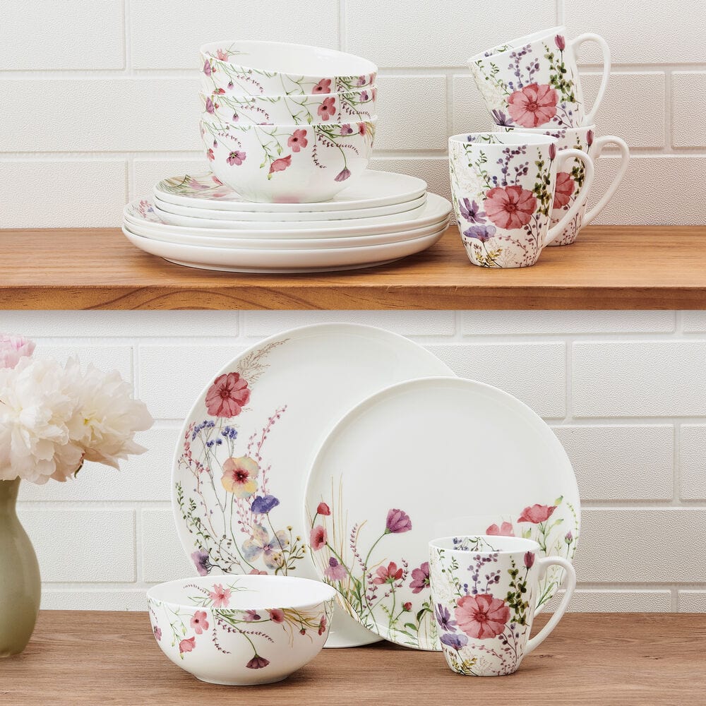 Floral ceramic dinnerware set on a wooden surface with a white tiled wall background.