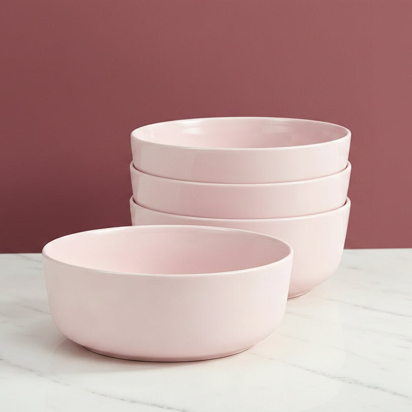 Set of pink ceramic bowls on a light gray surface with a neutral background